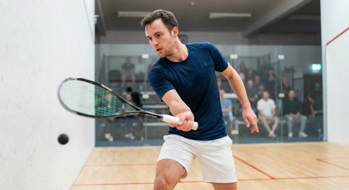 A squash player executing a precise forehand shot with focus on racket technique